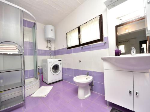 purpurowa i biała łazienka z umywalką i pralką w obiekcie Holiday Home Ena , Mali Iž 286 w mieście Mali Iž