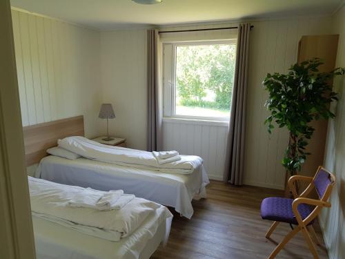 a room with two beds and a chair and a window at Bech's Hotell & Camping in Mo i Rana