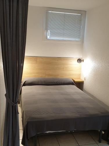 - une chambre avec un lit doté d'une fenêtre et d'un rideau dans l'établissement Studio Balaruc les Bains, vue sur l'étang de Thau classement 2 étoiles, à Balaruc-les-Bains