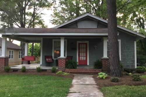 a small house with a red door and a porch at Mill Cottage in Tupelo