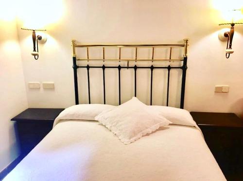 a bedroom with a large white bed and two lights at Hostal Posada La Panadera in Sepúlveda