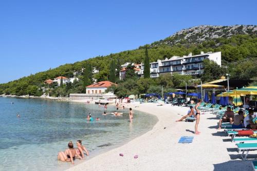 a beach with a bunch of people in the water at Apartment Adriana in Seget Vranjica