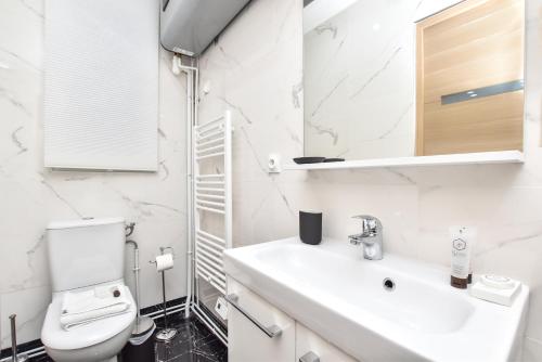 a white bathroom with a toilet and a sink at CMG Philharmonie de Paris/ Jaures in Paris