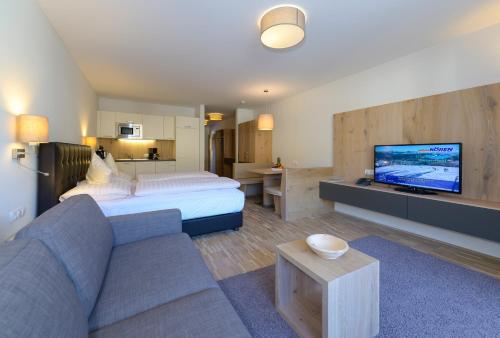 a hotel room with a bed and a couch and a tv at Appartementhotel Sonnenhof in Kössen