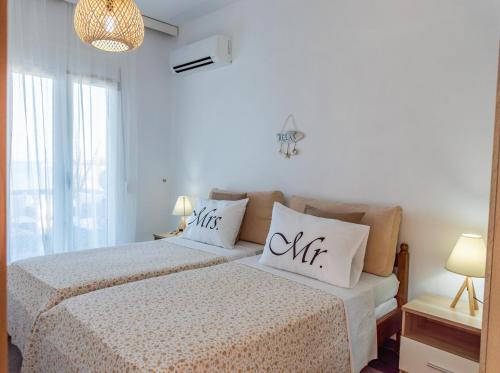a white bedroom with two beds and a window at Dimitras Luxus House in Archangelos