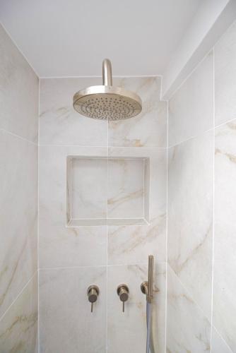 d'une douche avec des murs en marbre blanc et une installation lumineuse. dans l'établissement Luxury home in PARIS - Musée du Louvre, à Paris