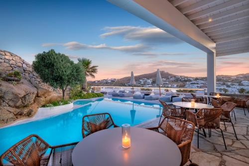 a patio with tables and chairs and a swimming pool at Deliades Hotel in Ornos