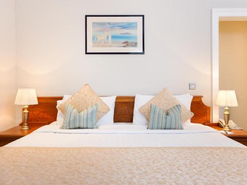 a bedroom with a bed with white sheets and pillows at Staunton Hotel - B&B in London