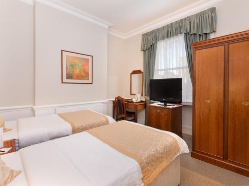 a hotel room with two beds and a television at Staunton Hotel - B&B in London