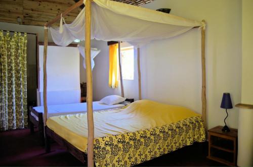 a bedroom with a bed with a canopy at Hotel le Lagon in Foulpointe