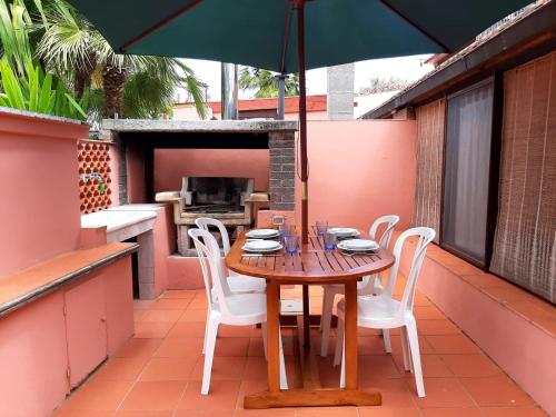 uma mesa de madeira e cadeiras numa varanda com um guarda-sol em Villa Very em Marina di Campo