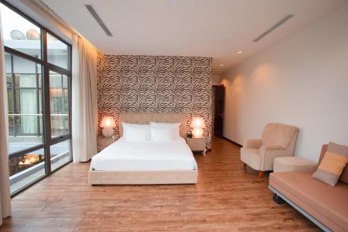 a bedroom with a bed and a couch and a chair at Bạch Yến T111-Happy Villa Đại Lải Resort in Vĩnh Phúc