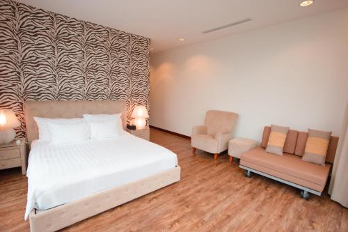 a bedroom with a white bed and two chairs at Bạch Yến T111-Happy Villa Đại Lải Resort in Vĩnh Phúc