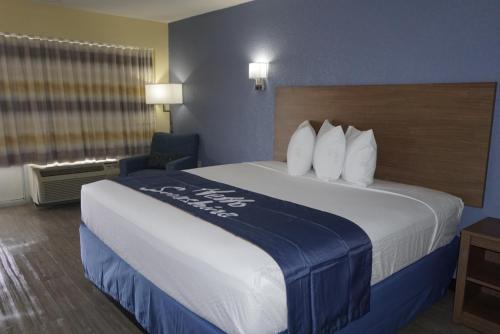 a hotel room with a large bed and a chair at Days Inn by Wyndham Apopka/Orlando in Orlando