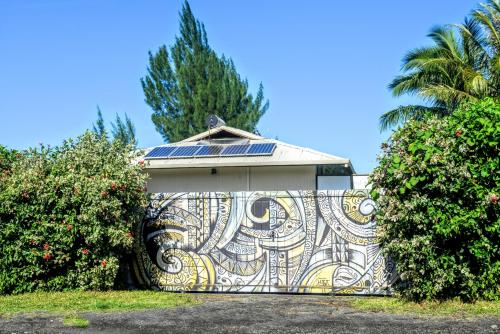 a house with a mosaic gate with a solar roof at TAHITI - Taharuu Houses Surf & Beach in Papara