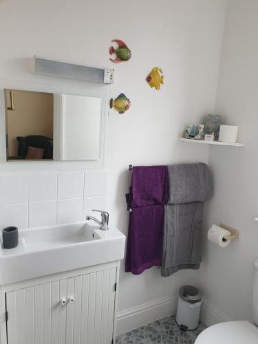 a bathroom with a sink and a mirror and purple towels at Highfield Guest House in Sheringham