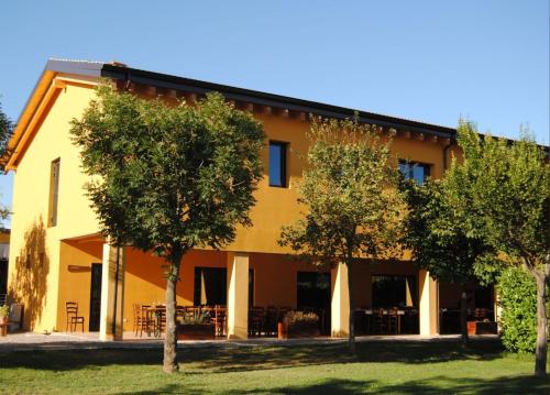 a yellow building with trees in front of it at Cascina Bosco Gerolo in Rivergaro