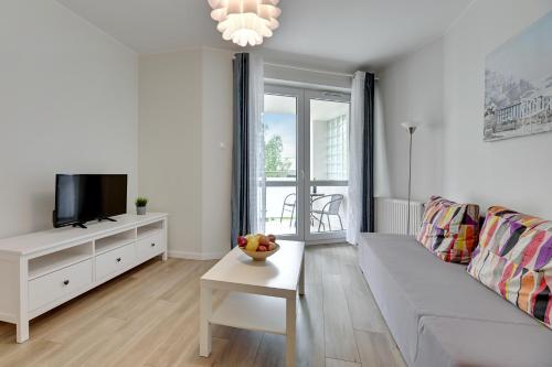 a white living room with a couch and a tv at TriApart Amber Jantar III in Jantar