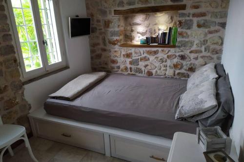 łóżko w pokoju z kamienną ścianą w obiekcie Klovino beach house w mieście Douviá