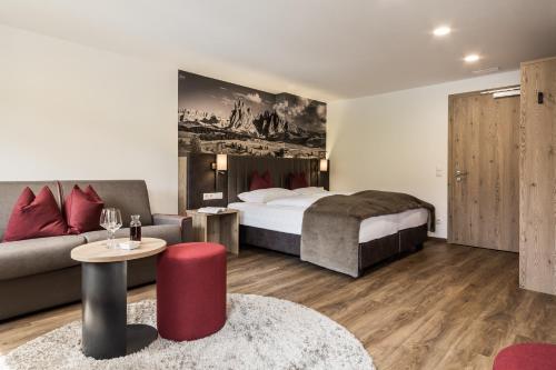 a hotel room with a bed and a couch at Hotel Zum Löwen - Al Leone in Meltina
