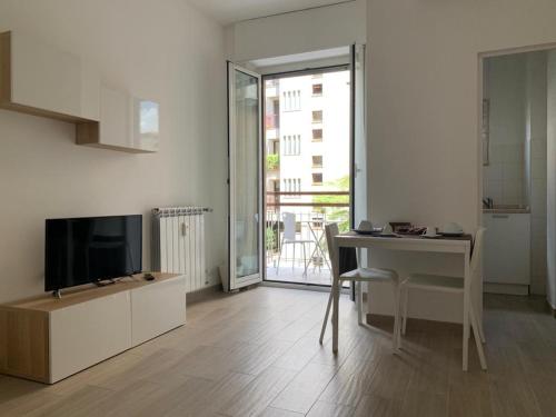 - un salon avec une table, une télévision et un bureau dans l'établissement My Petite Maison Milan, à Milan