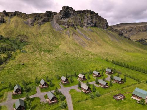 une vue aérienne sur une colline verdoyante avec des cabines dans l'établissement Hörgsland Cottages, à Hörgsland