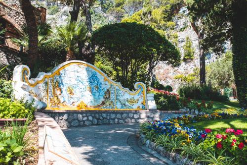 a bench in a garden with flowers and trees at Parco Augusto in Capri