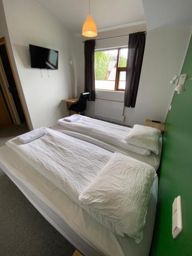 two beds in a room with a green wall at Hörgsland Guesthouse in Hörgsland