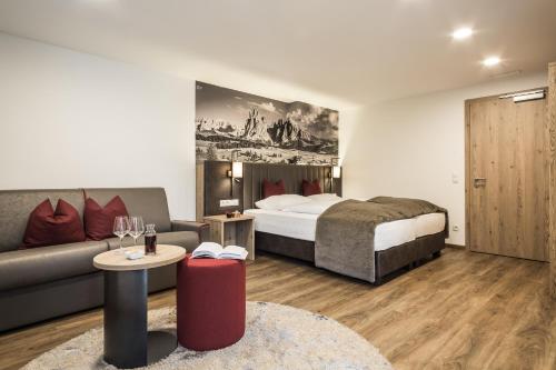 a hotel room with a bed and a couch at Hotel Zum Löwen - Al Leone in Meltina