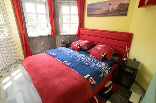 a bedroom with a red bed with red pillows at Centrum Lux 2 Apartmanok in Kaposvár