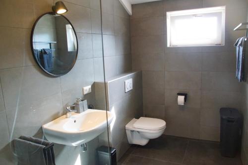 een badkamer met een wastafel, een toilet en een spiegel bij Vertoeven bij Verhoeven in Oud-Alblas