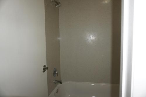 a bathroom with a tub and a shower with a mirror at Days Inn by Wyndham Apopka/Orlando in Orlando