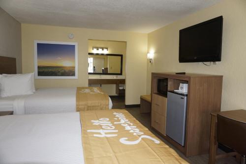 a hotel room with two beds and a flat screen tv at Days Inn by Wyndham Apopka/Orlando in Orlando