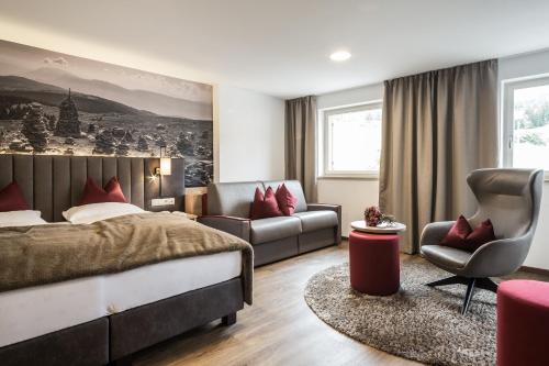 a bedroom with a bed and a couch and a chair at Hotel Zum Löwen - Al Leone in Meltina