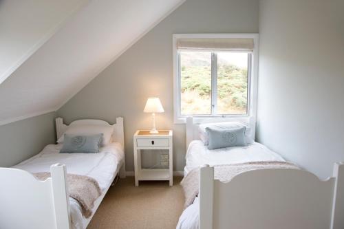 two twin beds in a room with a window at Buchanan Lodge - 60 acres on Wanaka lakefront in Wanaka