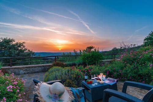 a patio with a table and chairs with the sunset at Borgo Fastelli - House in historical Borgo in Tuscany - Susino in Sarteano