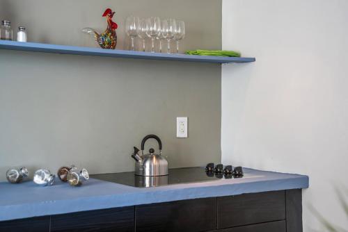 a kitchen counter with a tea kettle and glasses on a shelf at SoBe Lux Suites On Ocean in Miami Beach