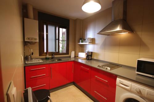 una cocina con armarios rojos y fregadero en Livingtarifa Apartamento Atardecer, en Tarifa