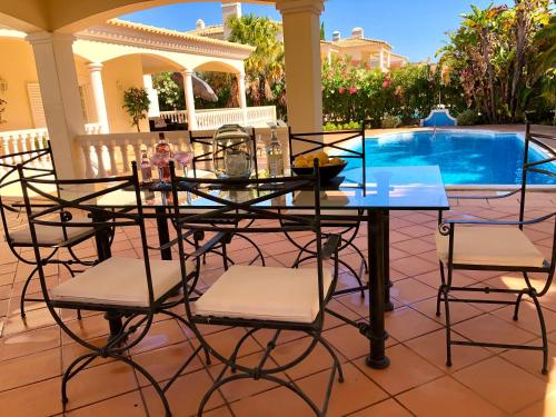 a glass table and chairs in front of a pool at Magellan House in Vilamoura