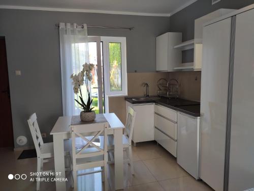 a kitchen with a table and a white table and chairs at Apartamenty i Pokoje Biala Hortensja in Ustronie Morskie