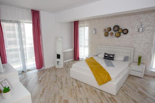 1 dormitorio blanco con 1 cama blanca grande y cortinas rojas en Apartamente MRM Residence en Mamaia-Sat