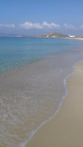 a sandy beach with the ocean and mountains in the background at Klimataria Studios in Agios Prokopios