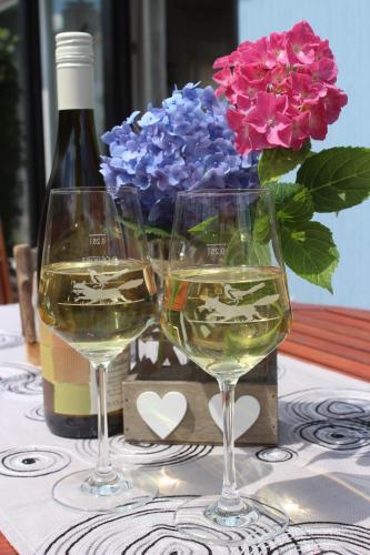 dos copas de vino blanco y un jarrón de flores en FEWO An der Ölmühle, en Heuchelheim-Klingen