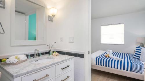 a white bathroom with a sink and a mirror at SoBe Lux Suites On Ocean in Miami Beach