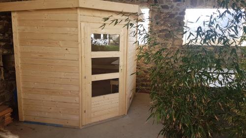 a wooden shed with a window next to a plant at L'Attrape Rêve Insolite in Saint-Vincent-de-Barrès