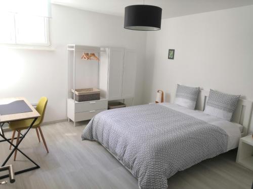 een slaapkamer met een bed, een tafel en een bureau bij Appart' O bernai in Obernai