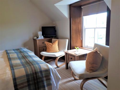 a bedroom with a bed and two chairs and a window at Corsewall Arms Guest House in Stranraer