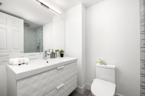 a white bathroom with a sink and a toilet at SoBe Lux Suites On Ocean in Miami Beach