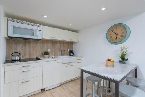 a kitchen with white cabinets and a clock on the wall at SoBe Lux Suites On Ocean in Miami Beach