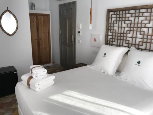 - une chambre avec un lit blanc et des serviettes dans l'établissement Casapuerta El Refugio, à Zahara de los Atunes